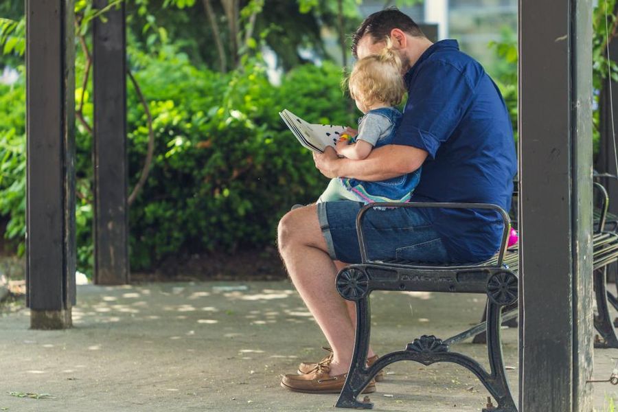 An adult reading aloud to a small child on a bench