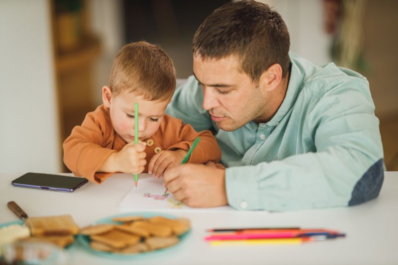 An adult and a child drawing together at a table
